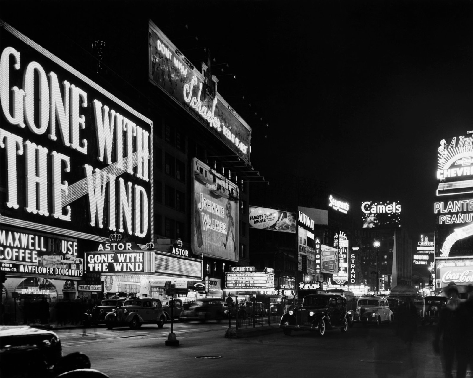 Avenida comercial iluminada por grandes rótulos publicitarios